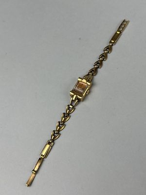 a close up of a gold bracelet on a white surface