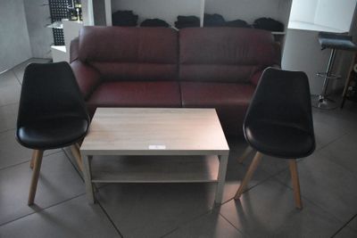 une photo d'un salon avec deux fauteuils noirs et une table basse