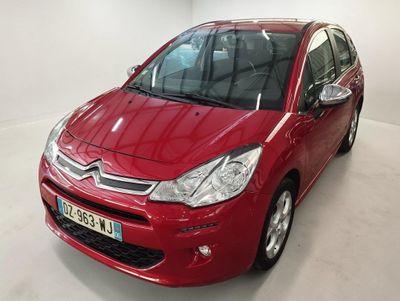 Une Citroën rouge est garée dans une pièce blanche