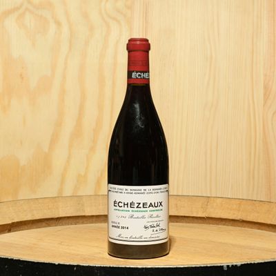 a bottle of wine sitting on top of a barrel