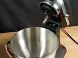 a large metal bowl on a wooden table with a blender