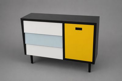 a black, white and yellow chest of drawers against a gray background