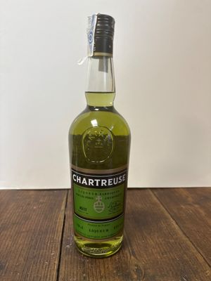 La bouteille de Chartreuse est posée sur une table en bois.