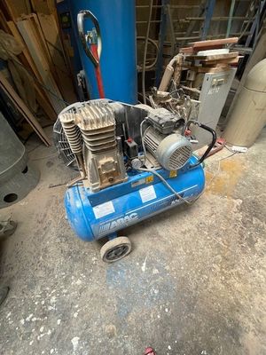 un compresseur d'air bleu posé par terre dans un garage