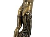 bronze statue of a woman on a rock with her hands on her head