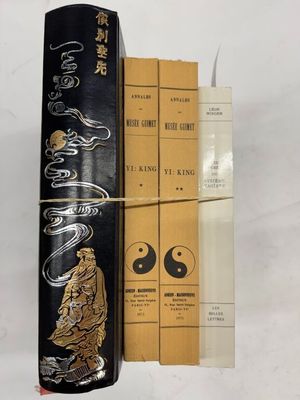 un vieux livre à la couverture noire posé au sommet d'une pile de livres