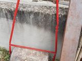 a red hand truck leaning against a wall next to a pile of wood
