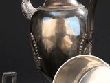 une théière en argent et une tasse en argent posées sur une table