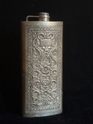 une flasque ancienne en argent sur fond noir, avec un fond noir