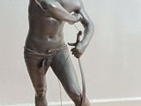 une statue représentant un homme tenant une batte de baseball, posée sur un plancher en bois