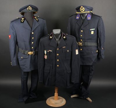 trois uniformes militaires exposés devant un fond noir