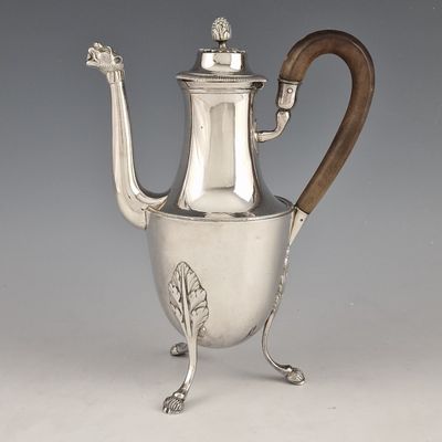 an antique silver coffee pot with a wooden handle on a stand