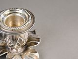 a silver candle holder with a flower design on it