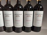 six bottles of red wine are lined up on a table