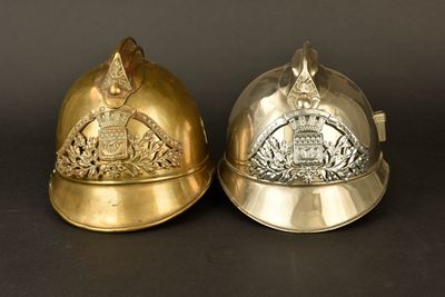 une paire de casques de pompier argentés et dorés sur fond noir