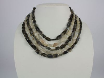 three strand necklace with black and white beads on a white mannequin