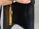 a person holding a black purse with a gold handle