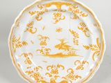 a yellow and white plate with a bird and flowers on it
