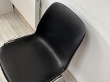 a black chair sitting in front of a radiator in the corner of a room