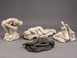three sculptures of a woman laying on a rock and a man laying on the ground