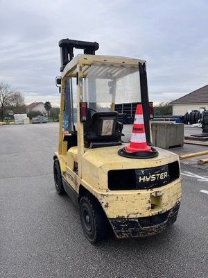 a yellow fork truck parked in a parking lot with a cone on top of it