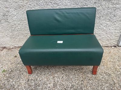 une chaise verte avec une étiquette, posée devant un mur