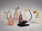 cinq types différents de flacons de parfum posés sur une surface blanche