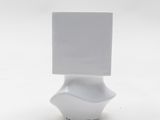a small white vase with a card on top of it