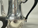 a silver teapot with a black handle on a table
