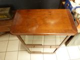 a small wooden table with a glass top on a tiled floor