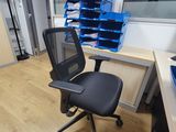a black office chair sitting in front of a computer desk