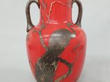 un vase rouge orné d'un oiseau perché sur une branche d'arbre