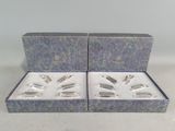 trois objets plaqués argent dans une boîte bleue posée sur une table