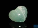 a close up of a green heart shaped stone on a black surface