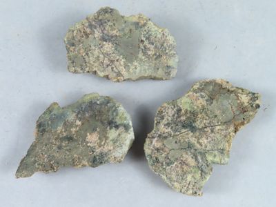trois morceaux de roche verte posés sur une surface blanche