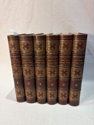 six old books lined up in a row on a white surface