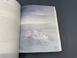 an open book with a picture of a mountain in the background