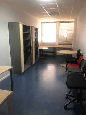 une pièce équipée d'un bureau, de chaises et d'un réfrigérateur