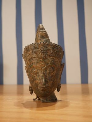 une statue représentant une tête de Bouddha posée sur une table en bois