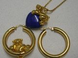 a gold necklace with a blue heart and a gold teddy bear on it