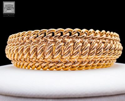 un gros plan d'un bracelet en or posé sur une assiette blanche
