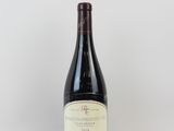 une bouteille de vin posée sur une table à côté d'un mur blanc