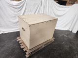 a wooden box sitting on a pallet in front of a white sheet
