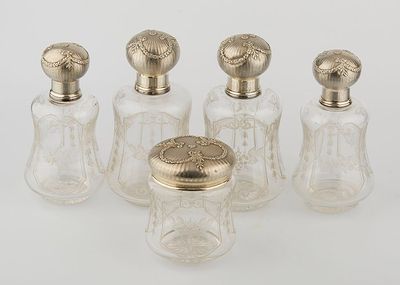 four glass bottles with gold tops and lids on a white surface