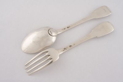 deux cuillères et une fourchette en argent sur une surface blanche