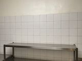 a stainless steel counter in a kitchen with white tiles on the walls