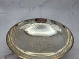 an antique silver plate on a marble table with a white background