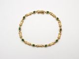 un bracelet en or orné d'émeraudes sur fond blanc