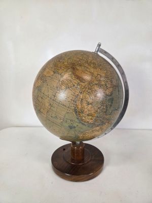 un vieux globe terrestre posé sur un socle en bois, avec un fond blanc