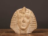 une photo représentant une sculpture représentant le visage d'une femme posée sur une table en bois
